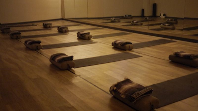 The studio set for class, with mats and bolsters under string lights